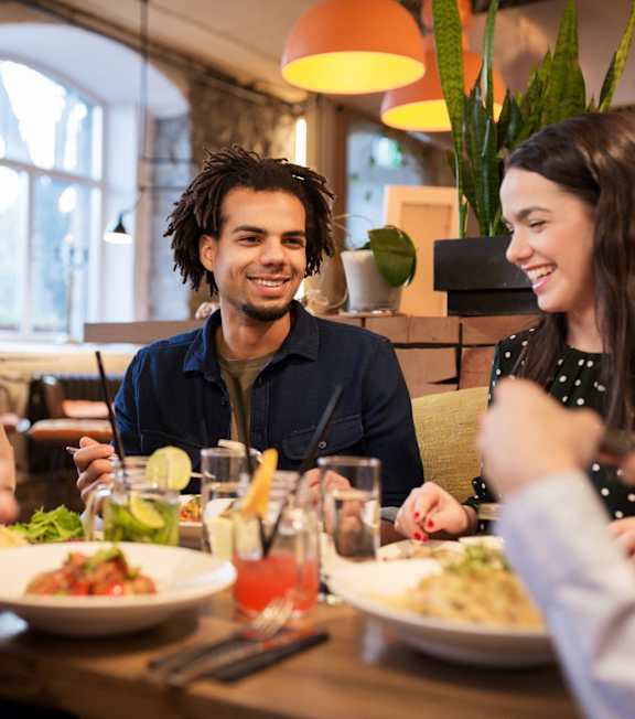 A group of people are sitting around a table eating food and drinking.