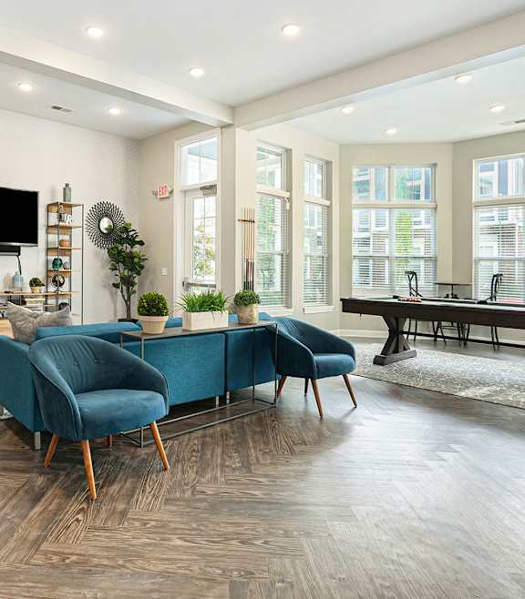 a living room with a blue couch and chairs and a pool table