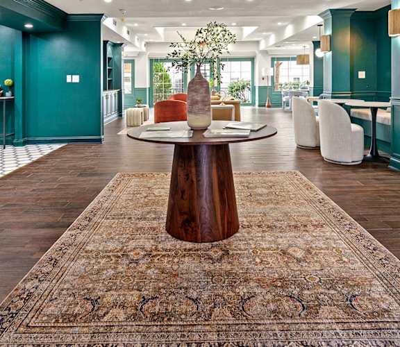 A large room with a rug in the middle and a table with a vase of flowers on it at 505 Collection in Atlanta, Georgia