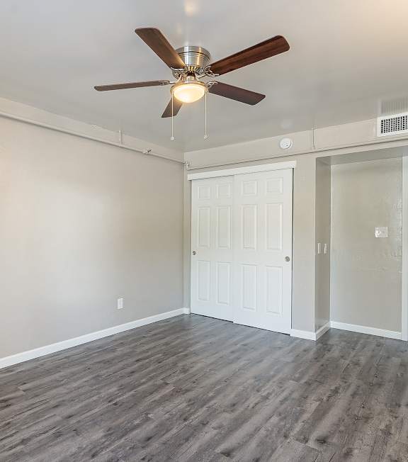 A room with a ceiling fan and wood flooring.