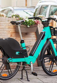 A rideshare bicycle is parked next to a wooden fence and planter