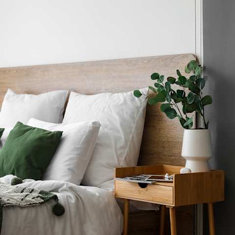 a bed with white pillows and a wooden headboard and a table with a