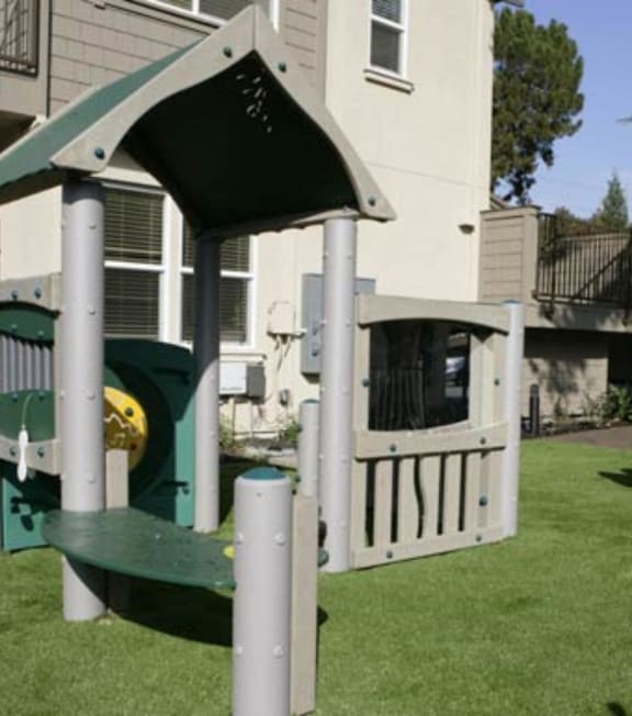a swing set in the backyard of a house with a toy car in the yard