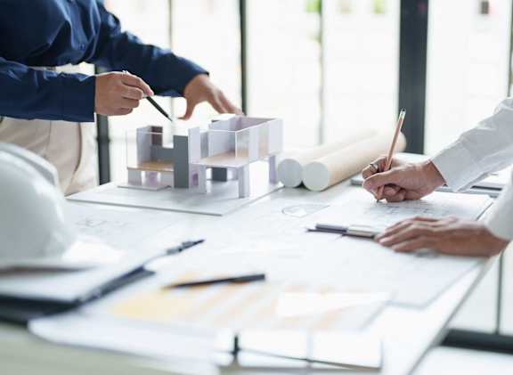 a group of people working on construction plans on a table