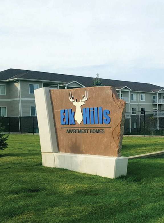 A sign for Eco Hills Apartment Homes sits in front of apartment buildings.