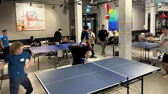A group of people playing ping pong in a room.