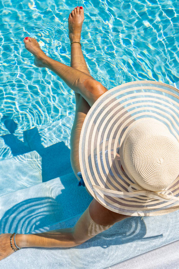 A large swimming pool with blue water and lounge chairs around it.