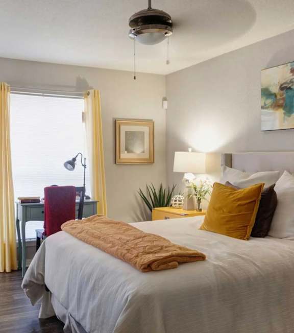 A bedroom with a large bed and a ceiling fan.