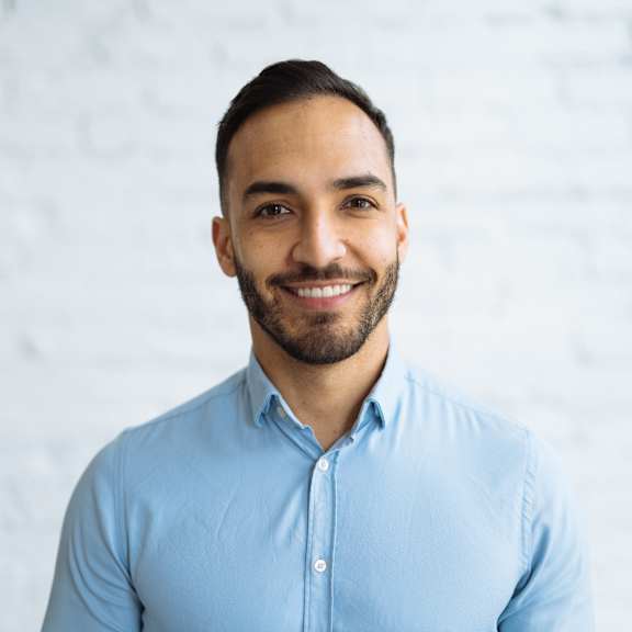 A man with a beard and short hair is wearing a light blue shirt.