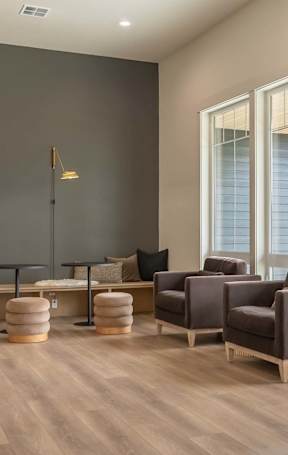 A modern living room with a fireplace and a large window overlooking a pool at Marcola Apartment Homes, Forest Grove, OR, 97477