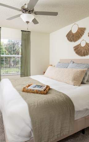 A bedroom with a bed, nightstand, and window.at The Lucille Apartments, Stuart, FL
