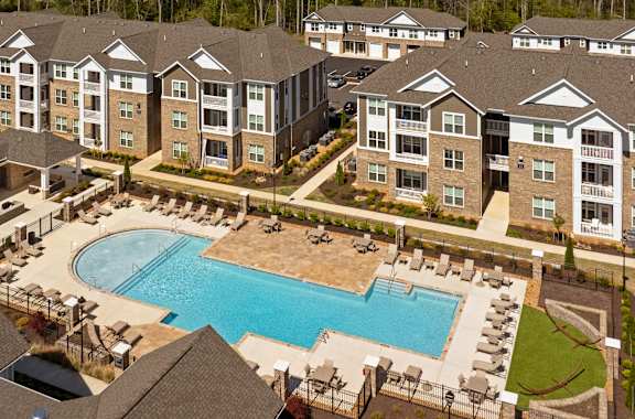 A large apartment complex with a swimming pool in the foreground.