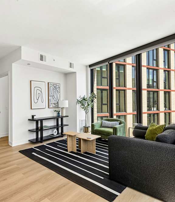 A modern living room with a grey sofa, a white coffee table, and a large window overlooking a snowy landscape.