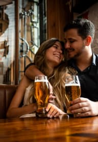 Couple Holding Each Other Smiling while Having Drinks