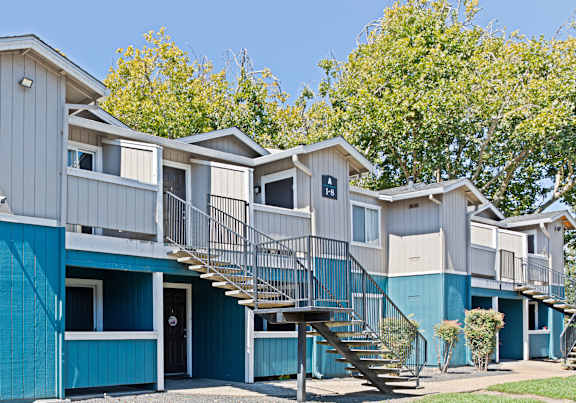 a row of blue condos with stairs and trees at Creekview Homes, Chico, CA