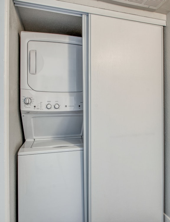 an empty kitchen with a refrigerator and a washer and dryer