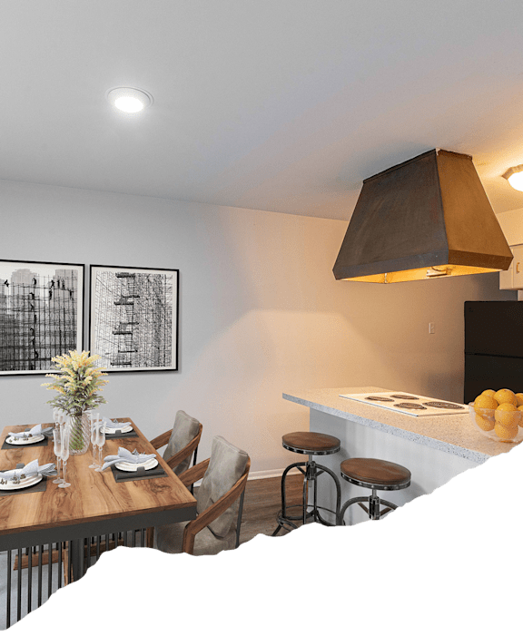 A kitchen with a table set for two and a vase of flowers on the table.