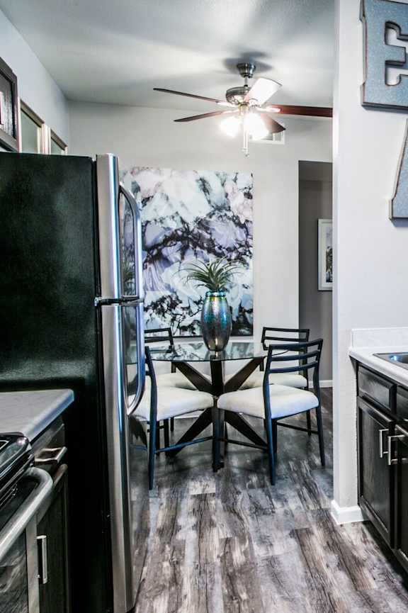 A kitchen with a black fridge and a table with chairs.