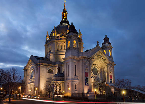 A large, illuminated church with a golden dome stands tall against a twilight sky.
