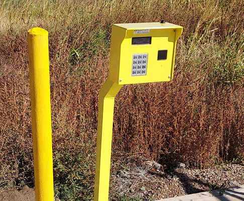 a yellow post with a keypad for entering a gate code