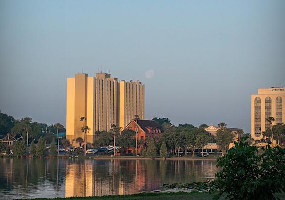 A large building is reflected in the water in front of it.
