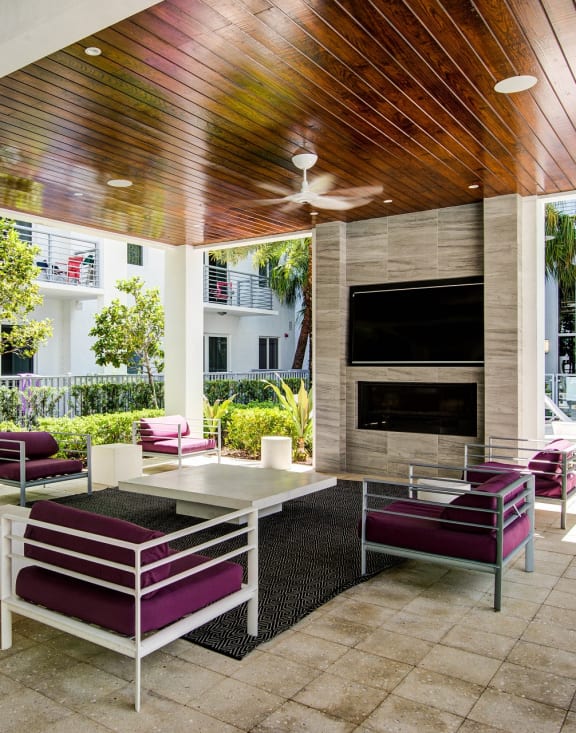 a patio with purple chairs and a fireplace