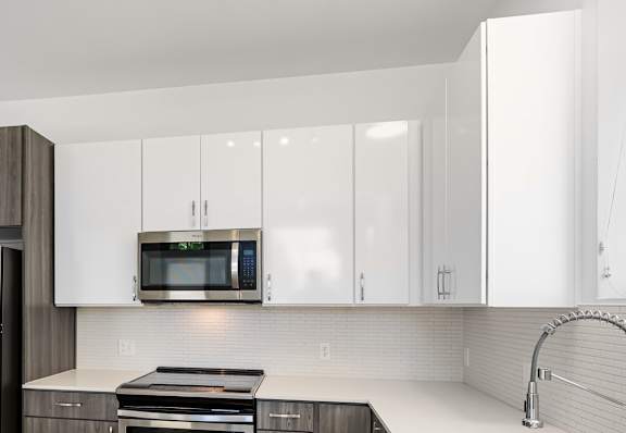 A modern kitchen with a white countertop and stainless steel appliances.