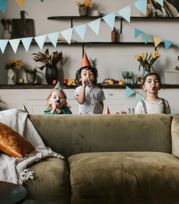 a group of children standing around a couch at a birthday party