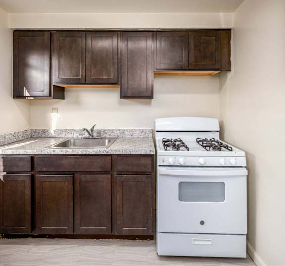 A kitchen with a white stove and brown cabinets.