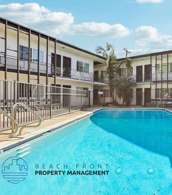 A pool with a hot tub and lounge chairs in front of a building.