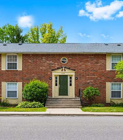 A red brick house with a green door and two windows.
