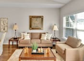 Thumbnail 7 of 12 - A living room with a couch, two chairs, a coffee table, and a painting on the wall.