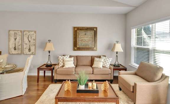 A living room with a couch, two chairs, a coffee table, and a painting on the wall.