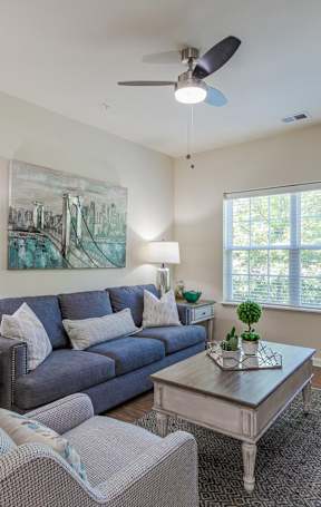 A living room with a grey couch, a coffee table, and a painting on the wall.