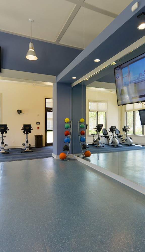 A gym with a blue floor and a television mounted on the wall.