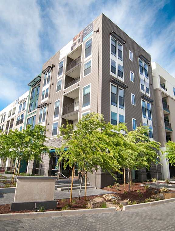 A modern apartment building with a parking lot in front.