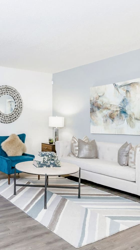 A modern living room with a grey sofa, a coffee table, and a painting on the wall.
