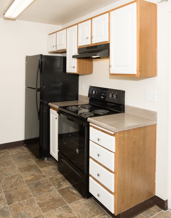 Martinazzi Village apartments vacant unit kitchen with white cabinets and black appliances
