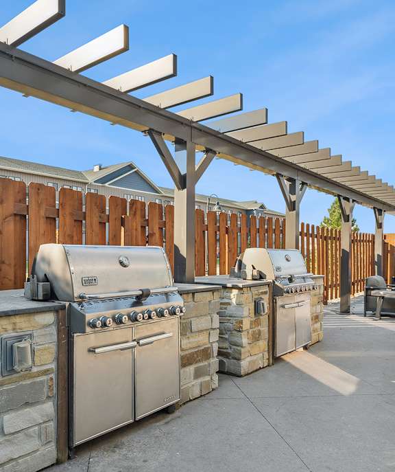 A patio with a grill and a pergola.