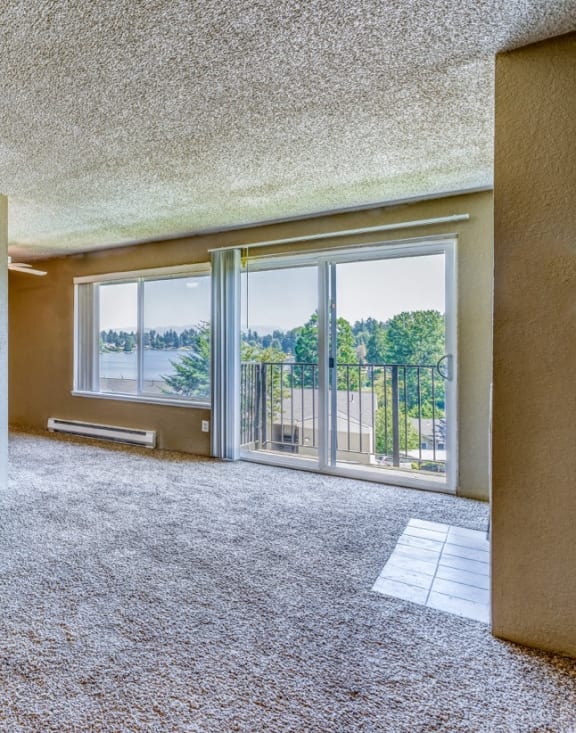 an empty living room with a balcony and a large window