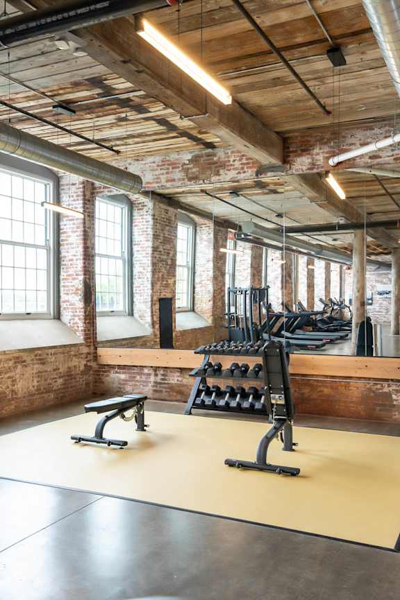 A gym with a brick wall and a row of windows.