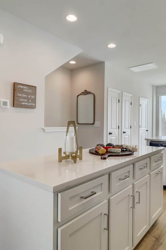 A kitchen with white cabinets and a large island.