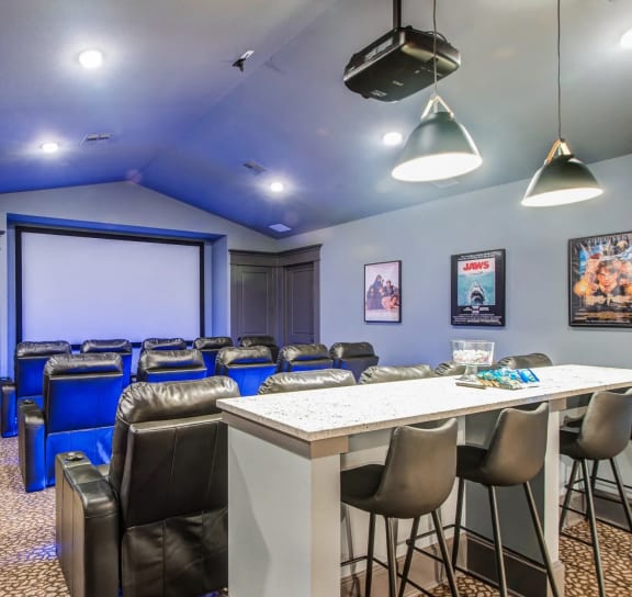a room with a bar and chairs and a projector screen