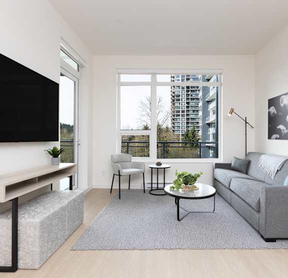 A modern living room with a large couch, a flat screen TV, and a wooden cabinet.