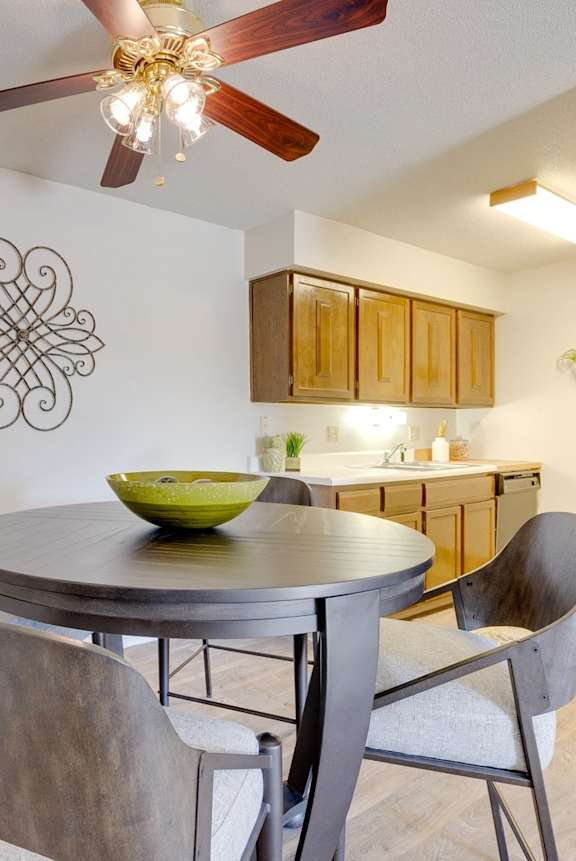 Dining area in the two-bedroom model unit at Olde English Village, with the kitchen visible in the background.