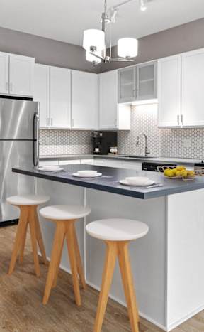 A kitchen with a white countertop and wooden stools.