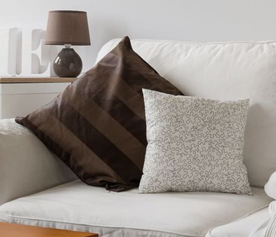 A white couch with brown and white pillows sits in a living room.