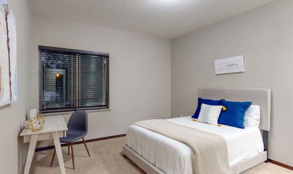 a bedroom with a bed and a desk and a window