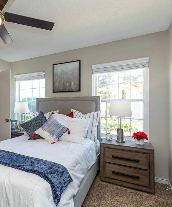 A bedroom with a large bed, a ceiling fan, and a window.