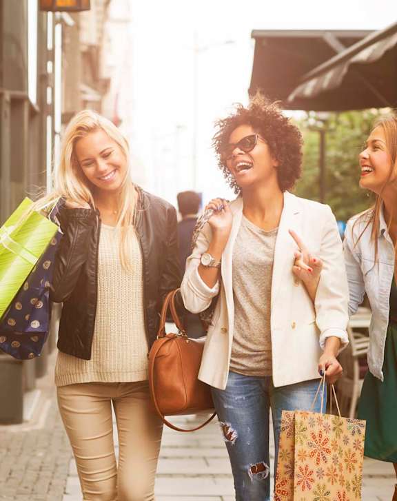 Three women walking down a street holding shopping bags.at La Jolla Canyon Apartments, San Diego, 92121